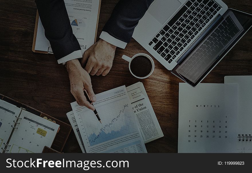 Person Holding Pen Beside White Printer Paper