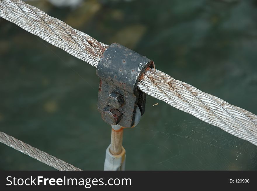 Rusty old bolt on a swingin bridge with a spider web.