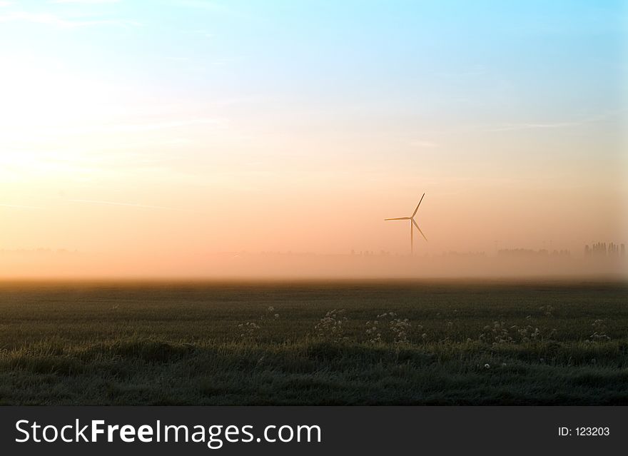 Wind turbine through early morning mist and sun. Whitemoor, Cambridgeshire, UK. Wind turbine through early morning mist and sun. Whitemoor, Cambridgeshire, UK