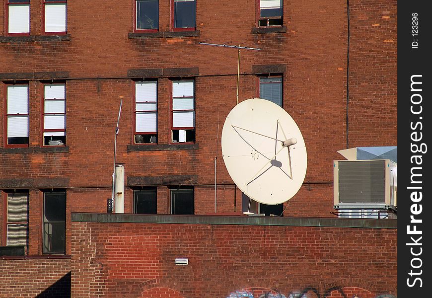 Large satellite dish sits on roof outside brick housing unit in northampton, massachusetts, new england. Large satellite dish sits on roof outside brick housing unit in northampton, massachusetts, new england