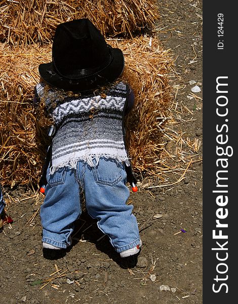 A toy doll dressed in farm clothing leans against a haystack at a farm in California. A toy doll dressed in farm clothing leans against a haystack at a farm in California.
