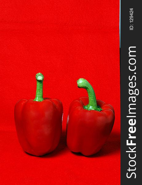 Two gorgeous, delicious, beautiful red peppers on a red felt background. Two gorgeous, delicious, beautiful red peppers on a red felt background