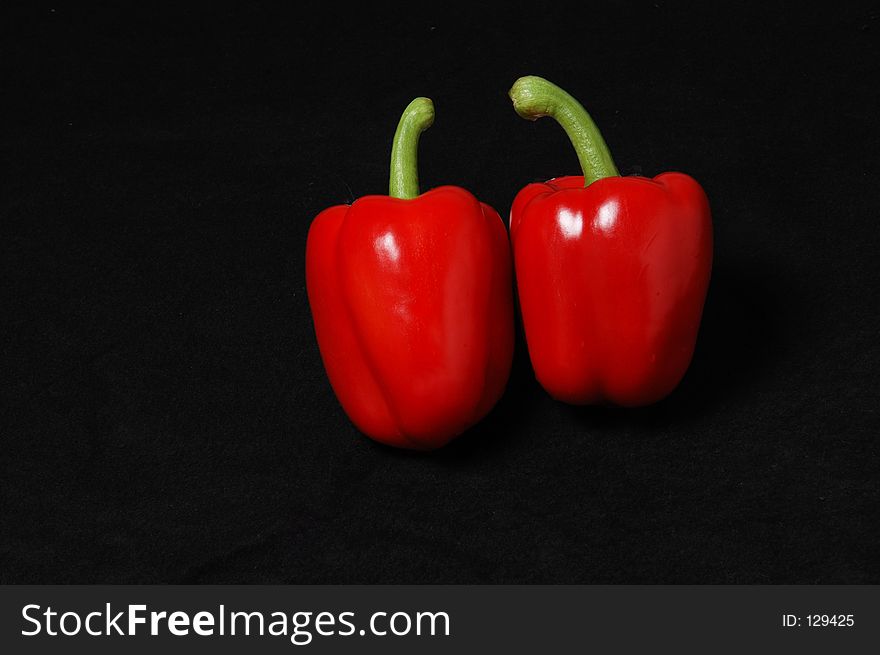 Two gorgeous, delicious, beautiful red peppers on a black felt background. Two gorgeous, delicious, beautiful red peppers on a black felt background