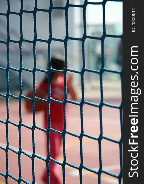 Girl playing ball out of focus behind a net
