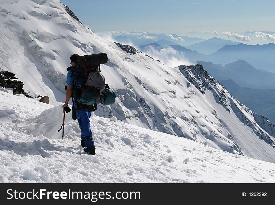Alpine climbing. Climber with backpack and ice-axe
