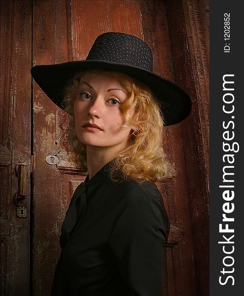 Portrait of attractive girl in a hat on a background of an old door