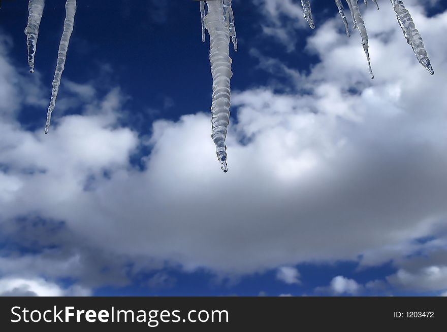 Icicles hanging with blue sky and clouds in the background. Icicles hanging with blue sky and clouds in the background