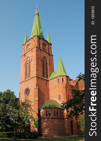 Ancient red brick church with green roof under clear sky