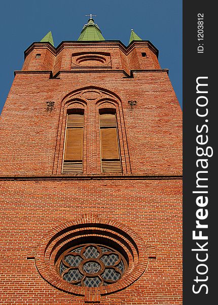 Ancient red brick church with green roof under clear sky