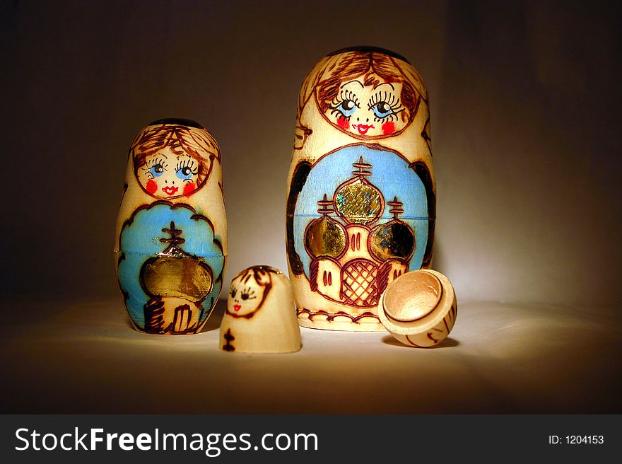 Two babushka dolls and one broken apart pictured together, light from the side. Two babushka dolls and one broken apart pictured together, light from the side.