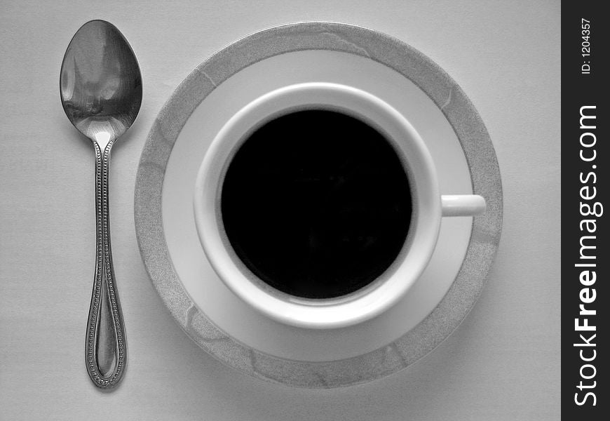 Cup of black coffee and spoon. Things that fit together. Black and white photo. Cup of black coffee and spoon. Things that fit together. Black and white photo.
