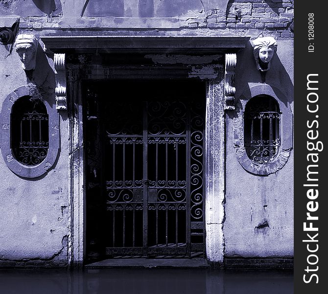 A very spooky looking gate in a building next to a canal in Venice. A very spooky looking gate in a building next to a canal in Venice.