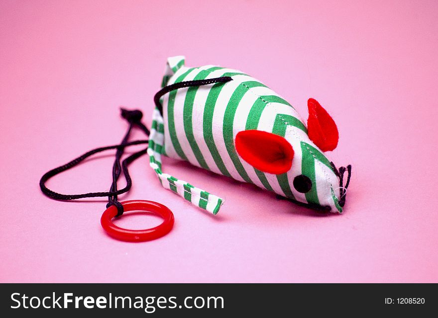 Stripped fun coloured cats toy mouse on a fun pink background concept image of being toyed or played with and no control. Stripped fun coloured cats toy mouse on a fun pink background concept image of being toyed or played with and no control