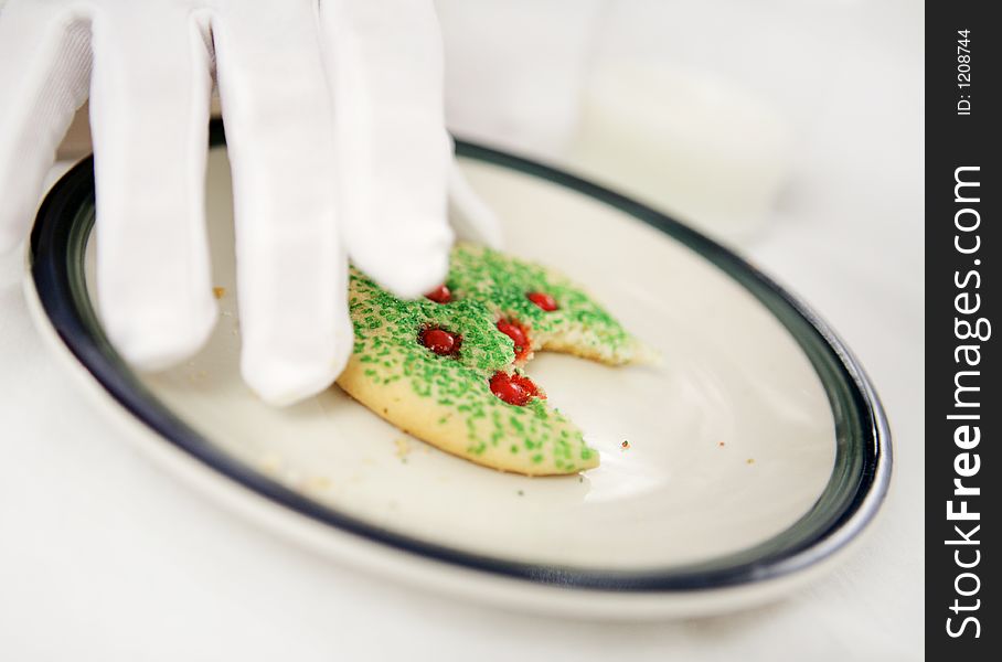 Santa's gloved hands putting down a half eaten Christmas cookie.  Shallow depth of field with focus on cookie. Santa's gloved hands putting down a half eaten Christmas cookie.  Shallow depth of field with focus on cookie.