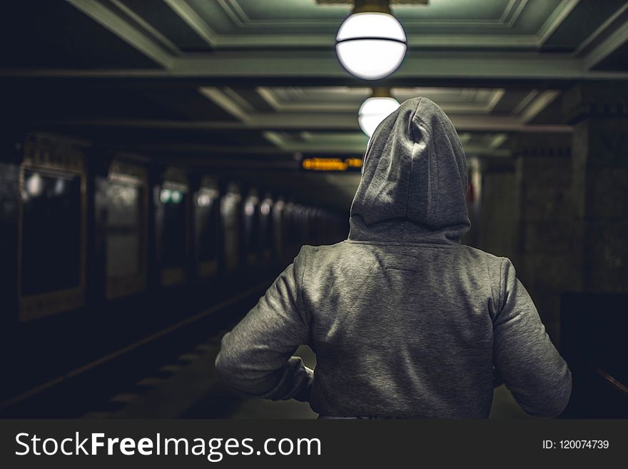 Person Wearing Gray Hooded Jacket in Train Station