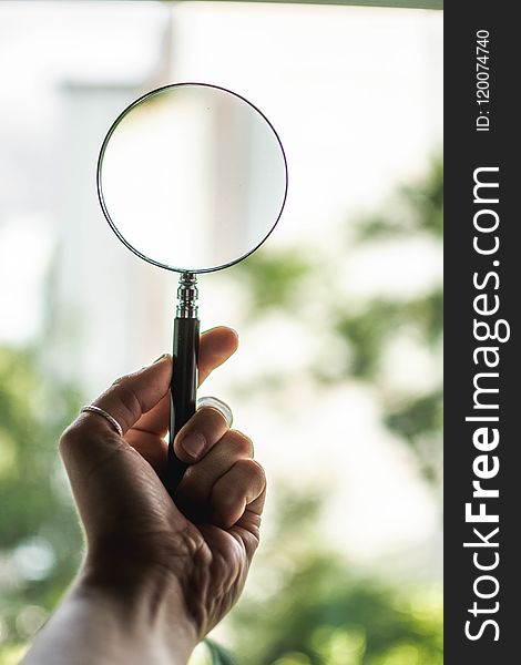 Tilt Shift Lens Photography of Person Holding Magnifying Glass