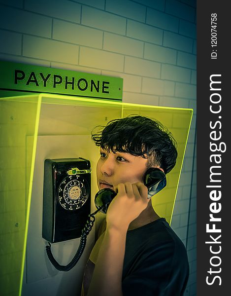 Man Holding Black Rotary Payphone