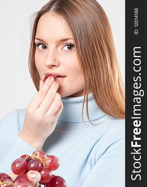 Young woman eating red grape from her hand. Young woman eating red grape from her hand