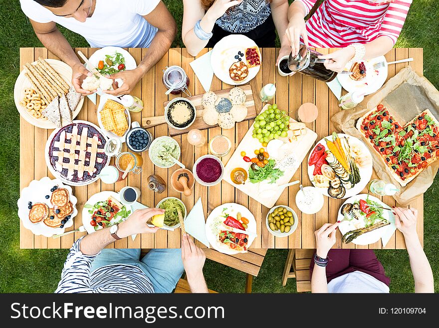 Top view on garden table with salad, fruits and pizza during out