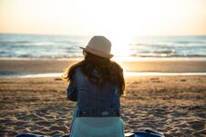 A Girl Sitting On The Beach At The Sunrise, Admiring And Enjoying The Sea Breeze Royalty Free Stock Photography