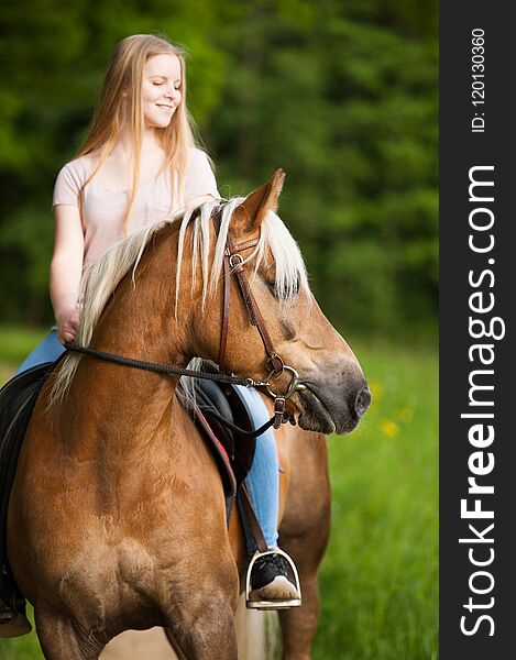 Girl with Haflinger rides along a path in summer landscape. Girl with Haflinger rides along a path in summer landscape