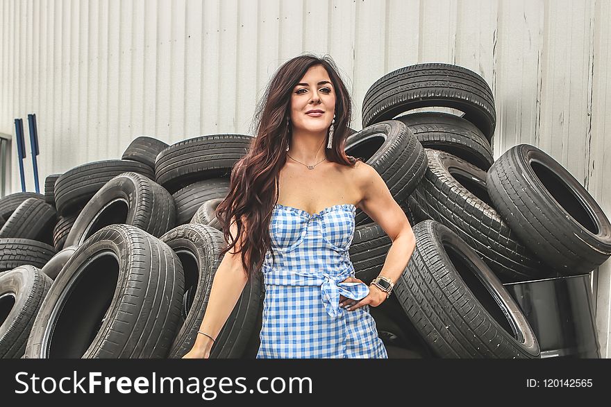 Woman Wearing Blue Flannel Dress Standing In Front Car Tires