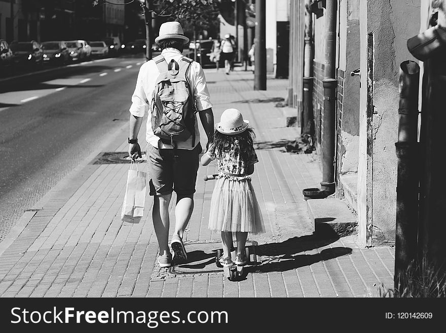 Man Holding Girl While Walking on Street