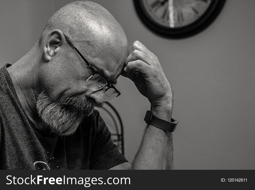 Grayscale Photo of Man Thinking in Front of Analog Wall Clock