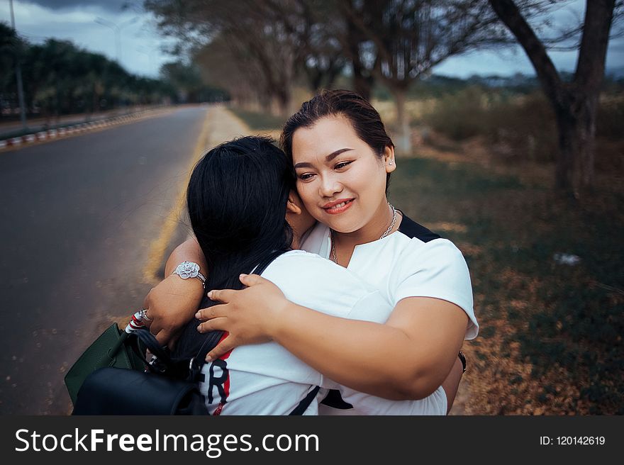 Two Women Hugging Each Other Standing on Pathway of the Road