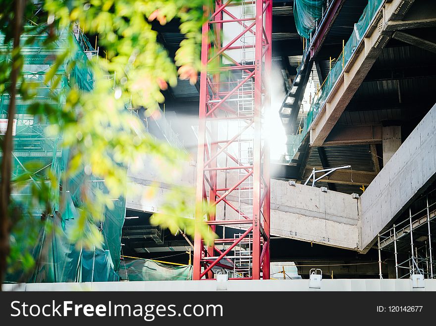 Green Leafed Tree Beside Red Metal Trusses and Building