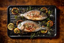 Grilled Fish, Sea Bream, Dorada With The Addition Of Spices, Herbs And Lemon On The Grill Plate Located On A Wooden Background, Royalty Free Stock Images Grilled Fish, Sea Bream, Dorada With The Addition Of Spices, Herbs And Lemon On The Grill Plate Located On A Wooden Background, Royalty Free Stock Images