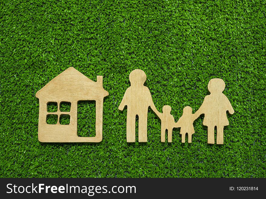 Family symbols and houses made of natural wood on the background of green grass symbolize the eco-house