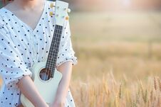 Beautiful Asian Woman Playing Ukulele And Relaxing At Barley Field In Summer On Sunset Time Stock Images