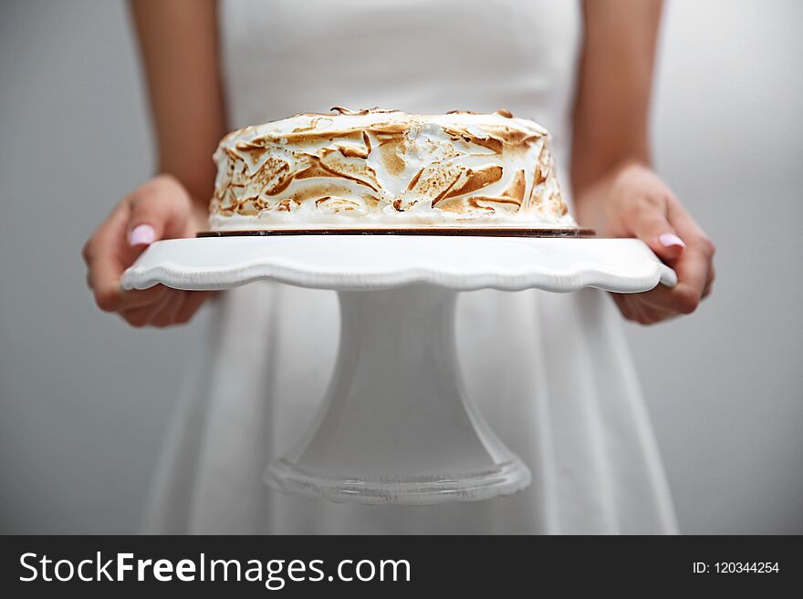 Woman holding birthday cake on white stand