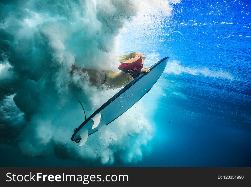 Surfer girl under wave against blue colored sea water surface. Surfer girl under wave against blue colored sea water surface