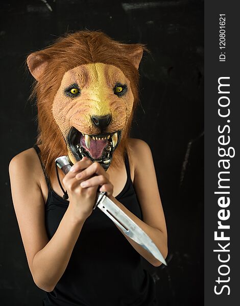female killer with lion mask holding short knife in dark black backgound. Halloween concept. female killer with lion mask holding short knife in dark black backgound. Halloween concept