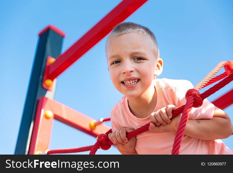 Happy little boy on children playground climbing frame