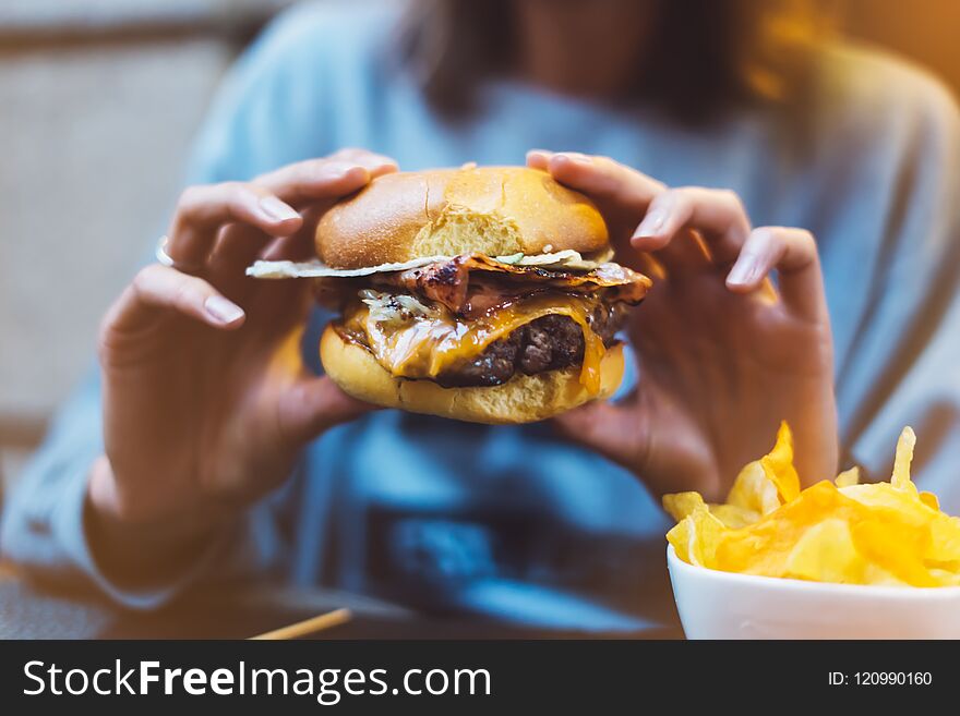 Young girl holding in female hands fast food burger, american unhealthy calories meal on background, mockup with copy space for te