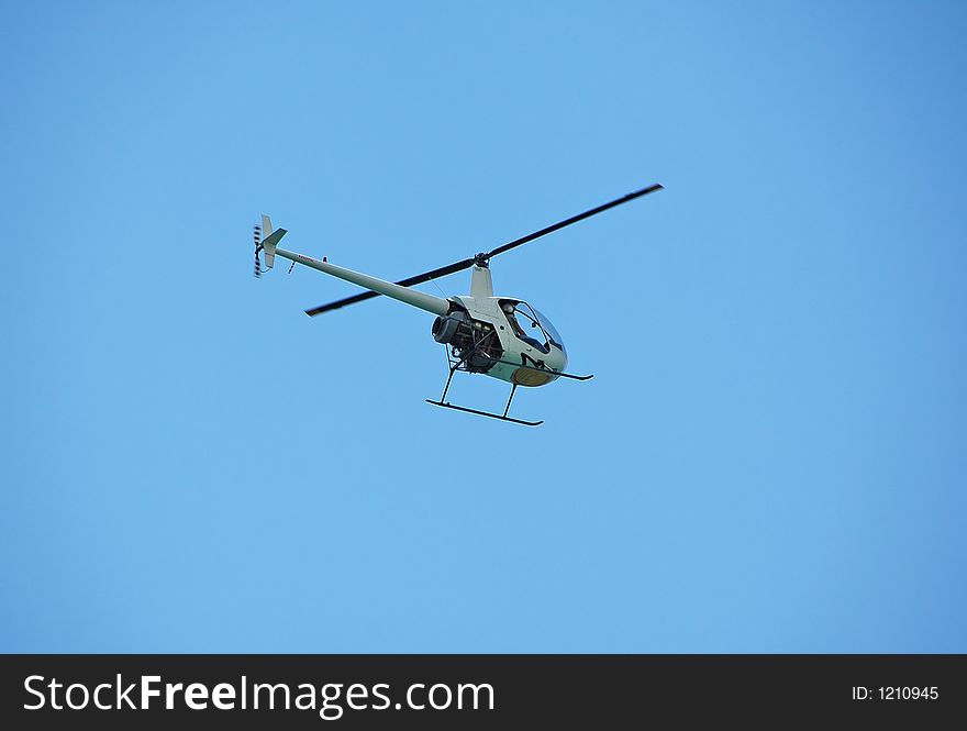 Light Robinson helicopter hovering over beach. Light Robinson helicopter hovering over beach