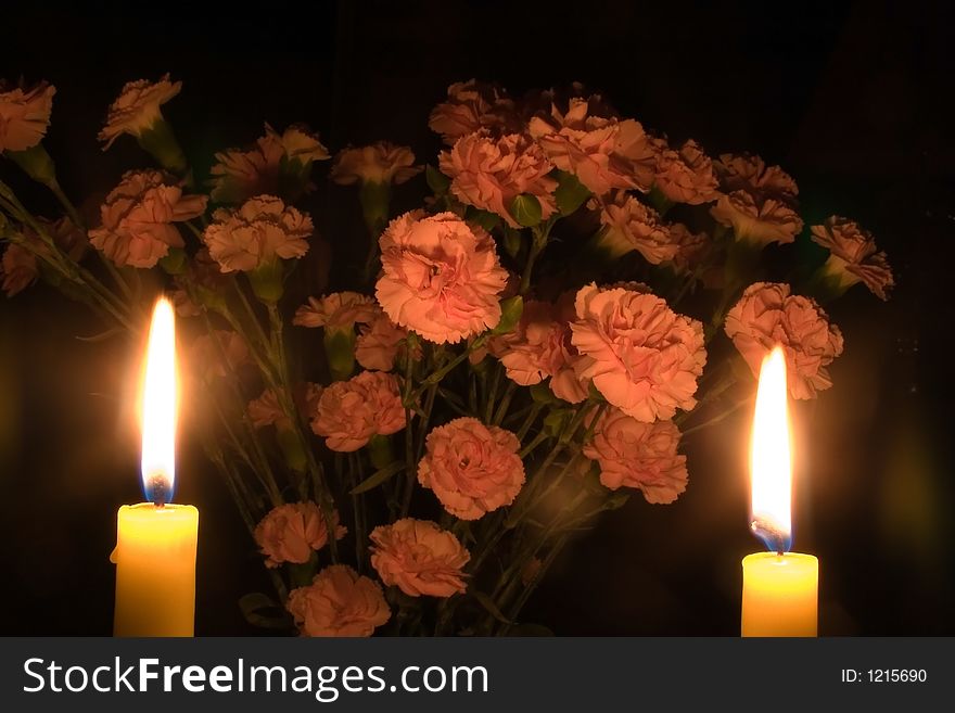 A bunch of carnations partly illuminated by two candles. A bunch of carnations partly illuminated by two candles