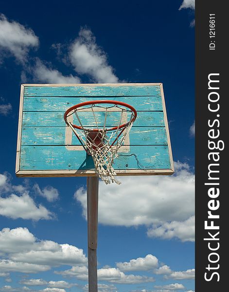 Basketball hoop and net against blue sky  and clouds. 
Vertical view.