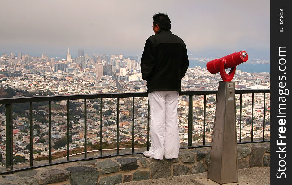 Typical coin-operated monocular on a viewing platform above a city and a man