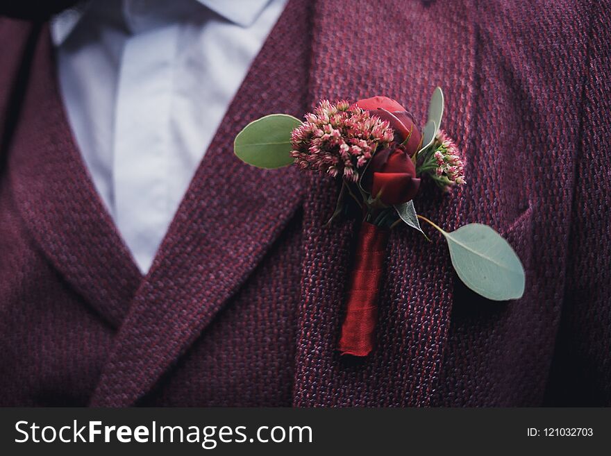 Groom and his boutonniere with a red ribbon. the jacket is dusty purple. wedding details. Groom and his boutonniere with a red ribbon. the jacket is dusty purple. wedding details