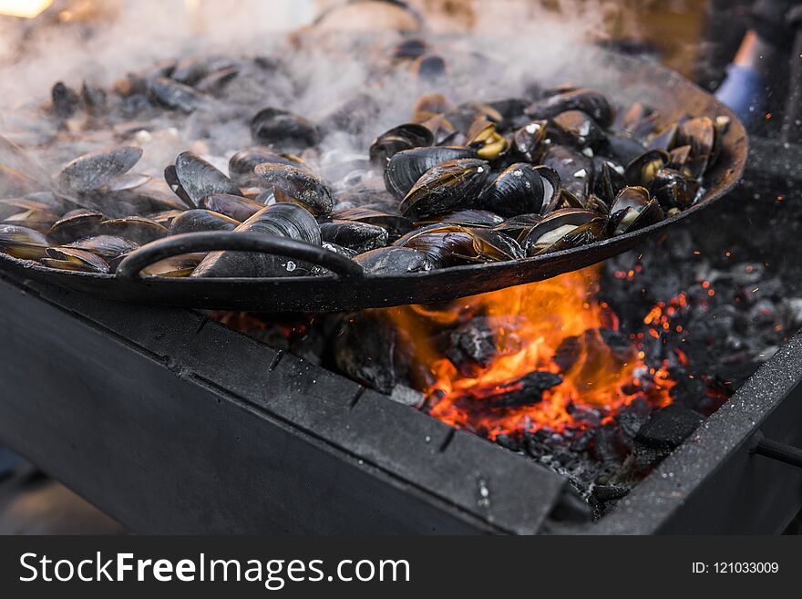 Fresh mussels at grill pan. Seafood barbecue outdoors. Picnic healthy food, mussels in shells. Plenty of mussel shells