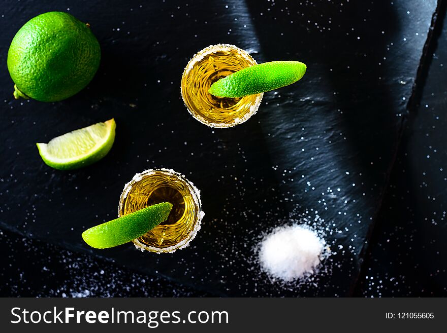 Mexican Gold Tequila with lime and salt on stone bar counter, flat lay, top view.