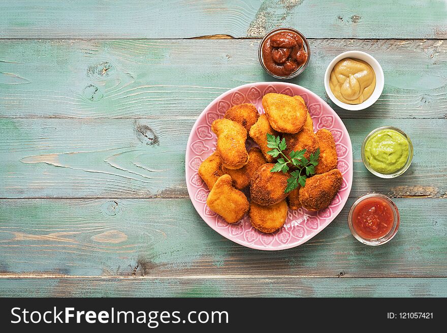 Chicken nuggets on a wooden green rustic table with a variety of sauces. Flat lay,copy space.