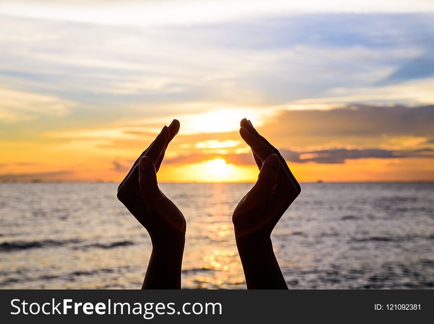 Woman hands holding the sun during sunrise or sunset.