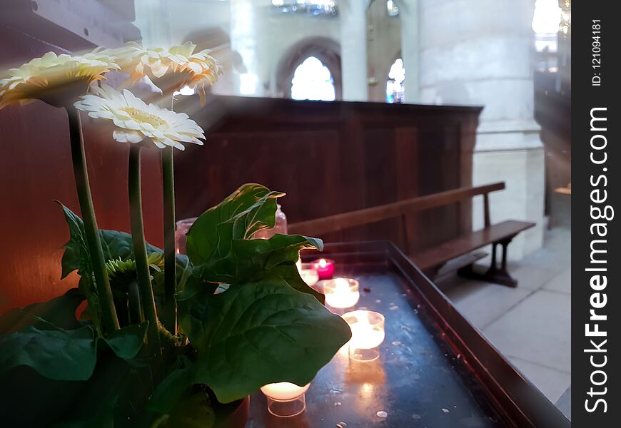 Candles burn in the temple, flowers under the rays from the stained glass.
