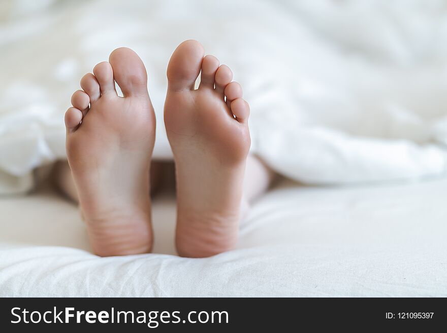 Close up of two feet in a bed.