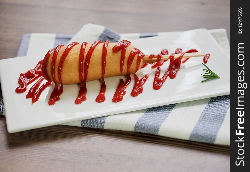 Hot dog with ketchup on a white plate